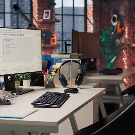 PC in startup office used to design and implement algorithms enabling machine learning. Technology unicorn venture workspace with PC used to conduct code reviews to fix bugs, jib down shot