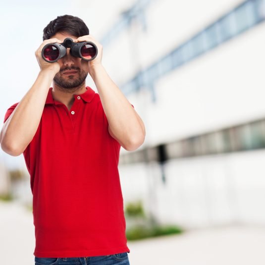 man looking throught binoculars